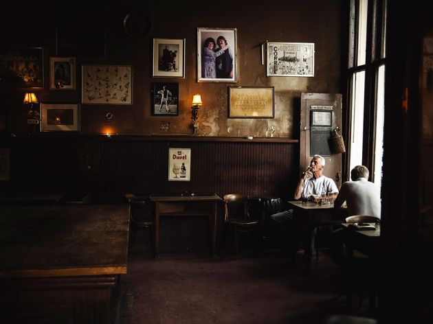 from National Geographic Photograph by Marko Savic"In a hidden street I found this cafe. It looked like a scenography for some movie. I loved the atmosphere and the pictures on the wall. The lighting was really dramatic, and the man with the cigar was in just the right place."